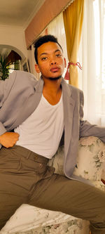 Young man sitting on bed at home