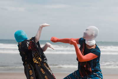 Women standing at beach against sky