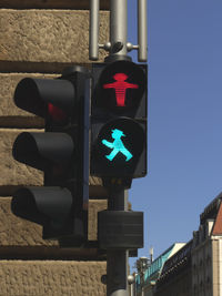 Low angle view of illuminated road signal in city against clear sky