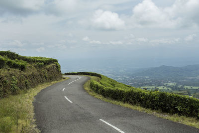 Empty road along landscape and against sky