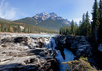 Stream flowing through rocks against sky