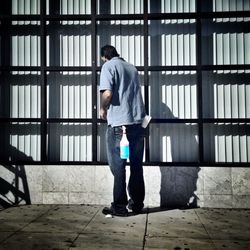 Full length rear view of manual worker cleaning window