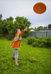 Full length of playful girl throwing plastic disc while standing at yard