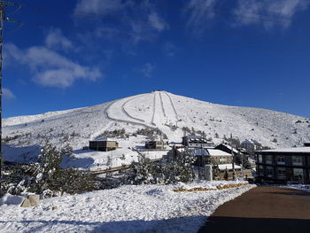 Snow covered buildings against blue sky