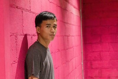 Portrait of man standing against pink wall