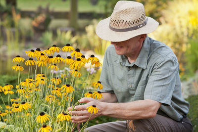 Midsection of person holding yellow flowering plants on field
