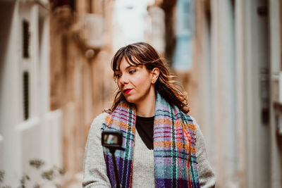 Beautiful young woman standing against wall