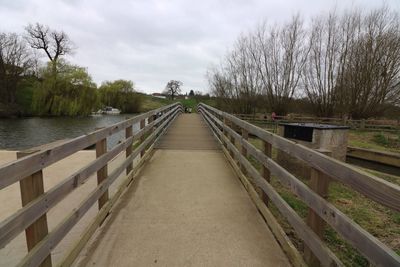 Footbridge amidst trees against sky