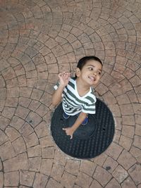 High angle view of boy standing on manhole