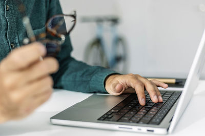 Hand of freelancer typing on laptop keyboard at desk