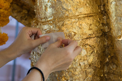 Close-up of hands putting gold foil