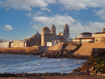 View of the famous cathedral of cadiz at sunset from the beach. tourism concept