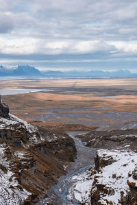 High angle view of stream flowing amidst snow covered mountains in valley