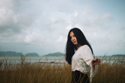 Asian long hair girl in white clothes enjoys life in nature coastal field.