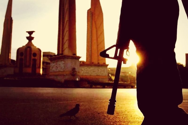 bird, animal themes, religion, statue, built structure, spirituality, sculpture, sunlight, silhouette, place of worship, sun, architecture, animals in the wild, human representation, low angle view, sunset, wildlife, sunbeam, cross