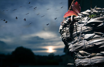 Wicker basket with birds flying against cloudy sky