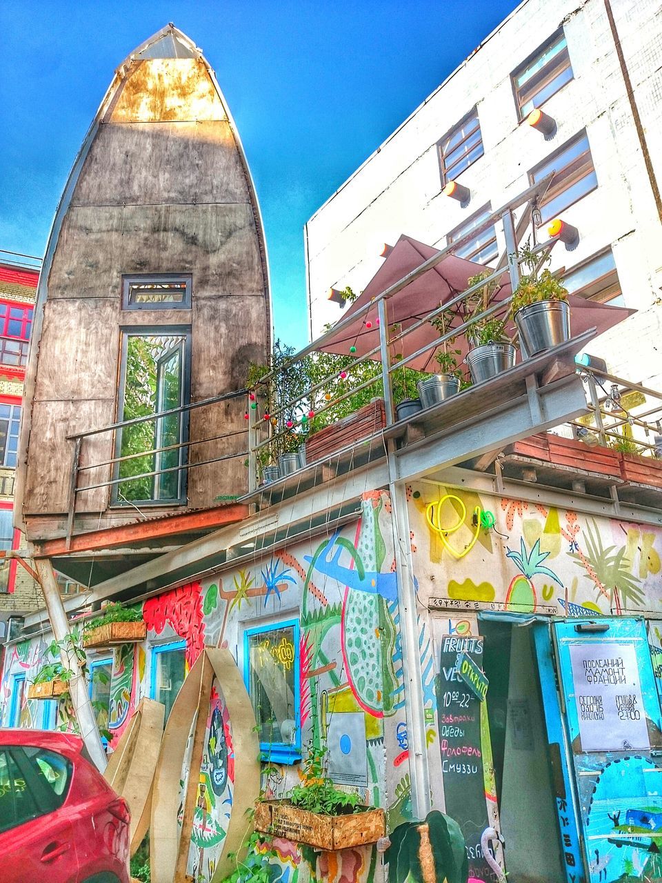 architecture, built structure, building exterior, low angle view, blue, window, building, arch, graffiti, clear sky, text, wall - building feature, day, residential structure, outdoors, facade, residential building, multi colored, sky, no people