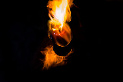 Close-up of lit candle against black background