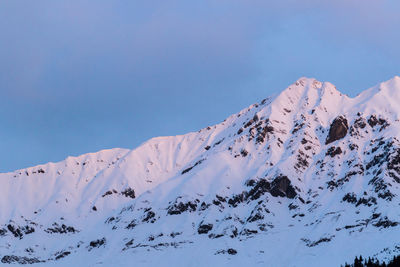 Low angle view of snow covered mountain against blue sky