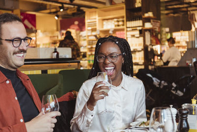 Happy woman having wine with male friend during party in restaurant