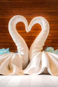 Close-up of towels forming swans on bed