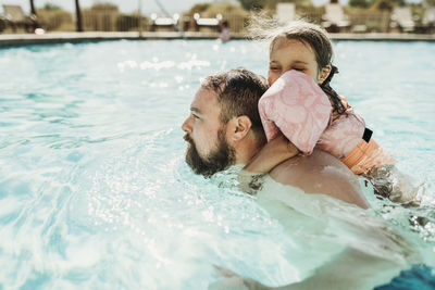 Rear view of father with swimming pool in water