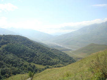 Scenic view of valley and mountains against sky