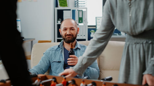 Portrait of man holding beer while sitting at home