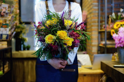 Midsection of florist holding bouquet at flower shop