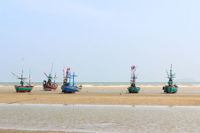 Fishing boats on beach against clear sky