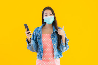 Portrait of a beautiful young woman against yellow background