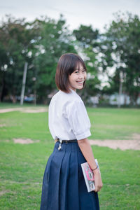 Portrait of a smiling young woman standing on field