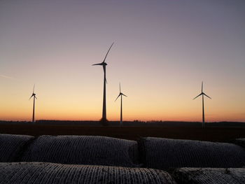 Windmill on field against sky during sunset