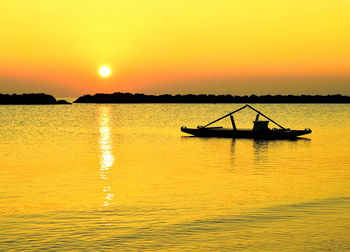 Silhouette boat in sea against orange sky