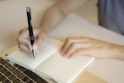 Midsection of woman reading book on table