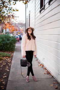 Full length of young woman standing against building