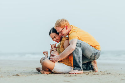 Father and son on beach against sky