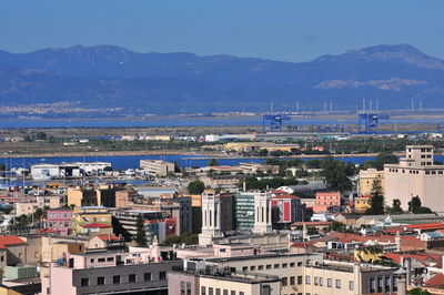 High angle view of townscape by sea against mountains
