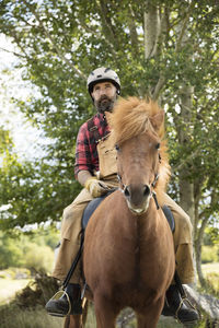 Male farmer in helmet riding horse