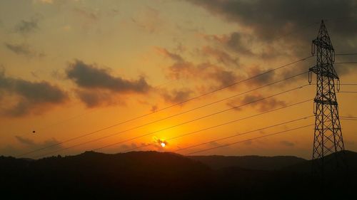 Silhouette of electricity pylon at sunset