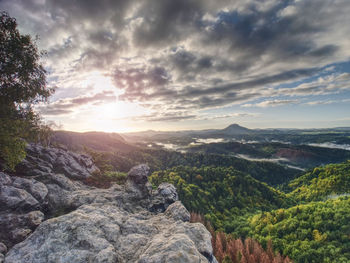 Peak of sandstone rock with view into colorful mist in morning valley. blue daybreak sun hidden