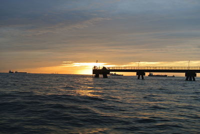 Silhouette boat in sea against sky during sunset