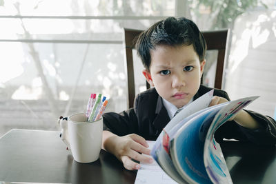 Portrait of boy looking away while sitting on table