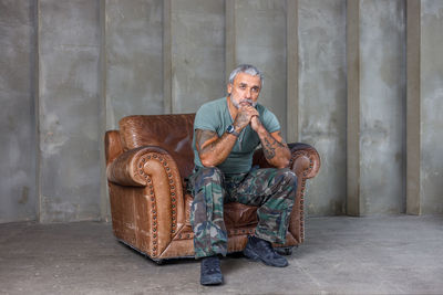 Low angle view of senior man sitting against wall