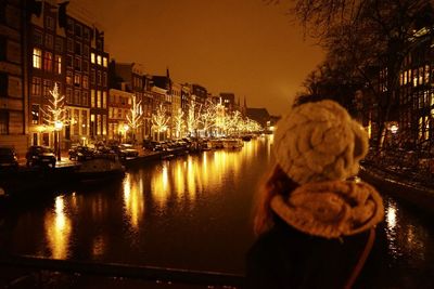 Rear view of woman in illuminated city against clear sky at night