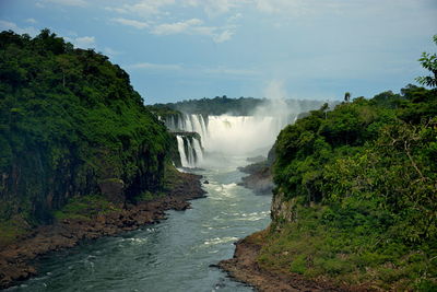 Scenic view of waterfall in forest against sky