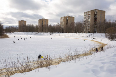 Snow covered field by buildings against sky