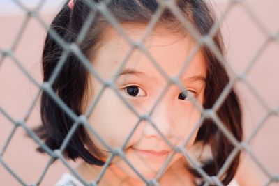 Portrait of child girl seen through chainlink fence