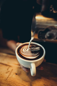 Milk pouring in coffee cup on table