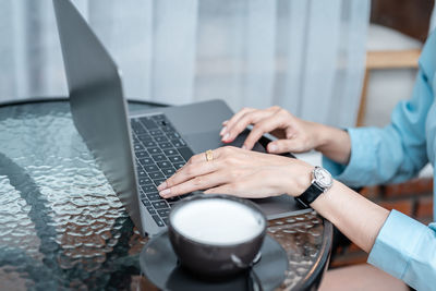 Midsection of woman using laptop on table